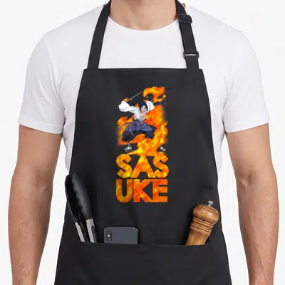 Tablier de cuisine noir avec Sasuke et des flammes orange formant le mot SASUKE