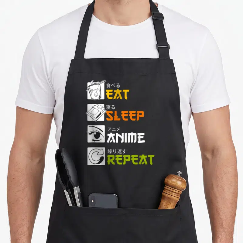 Tablier de cuisine noir avec quatre cases illustrant manger dormir regarder des anime et répéter le cycle en lettres colorées.