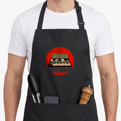 Tablier de cuisine noir avec illustration synthétiseur vintage sur cercle rouge et texte japonais doré.