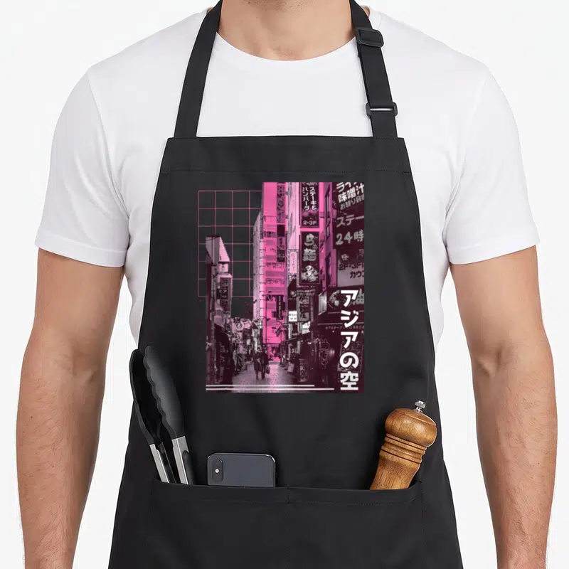 Tablier de cuisine noir avec photographie de ville japonaise rose et violet, lettres de rue et silhouettes de passants.