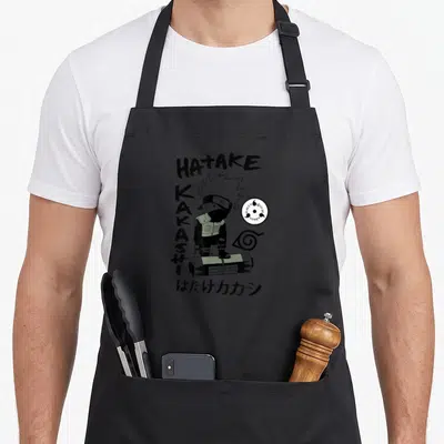 Tablier de cuisine noir avec illustration de Hatake Kakashi en style chibi et texte vertical HA+AKE KAKASHI