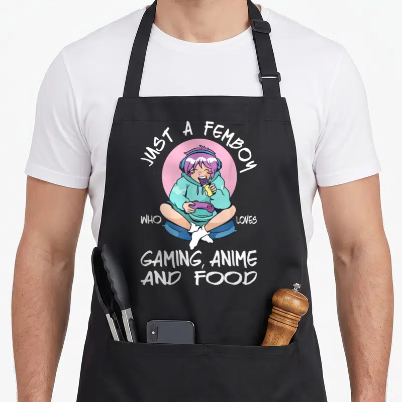Tablier de cuisine noir avec illustration d'un personnage femboy aux cheveux violets mangeant une barre tout en jouant à la manette.