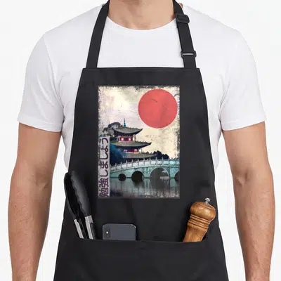 Tablier de cuisine noir avec illustration d'un temple japonais, d'un pont et d'un soleil rouge sur fond texturé vintage.
