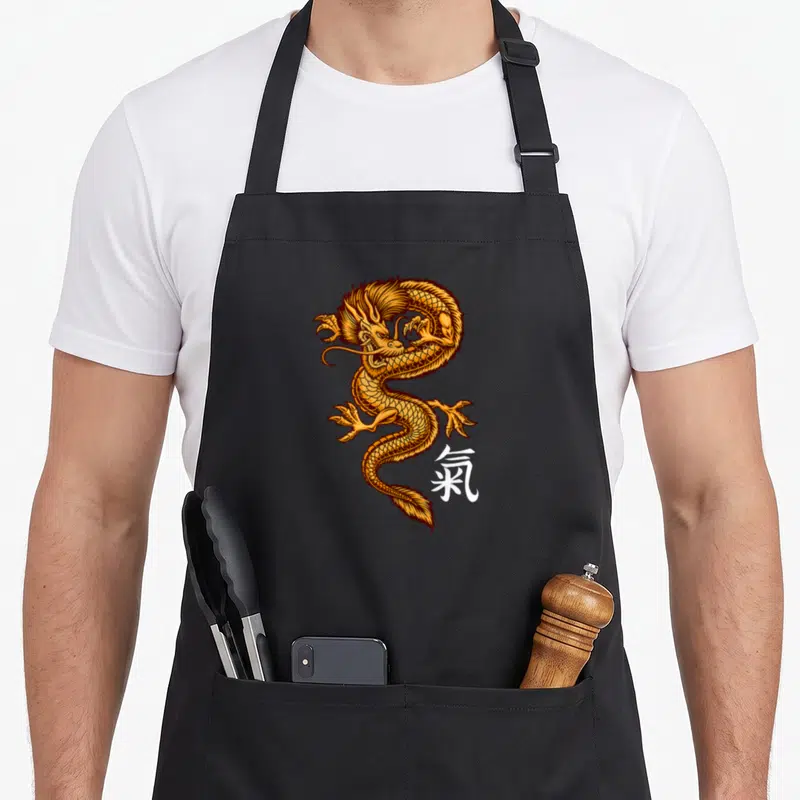 Tablier de cuisine noir avec illustration dragon doré et symbole kanji blanc sur le côté.