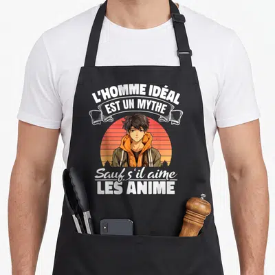 Tablier de cuisine noir avec illustration d'un garçon manga et texte blanc L'homme idéal est un mythe sauf s'il aime les anime sur fond orange.