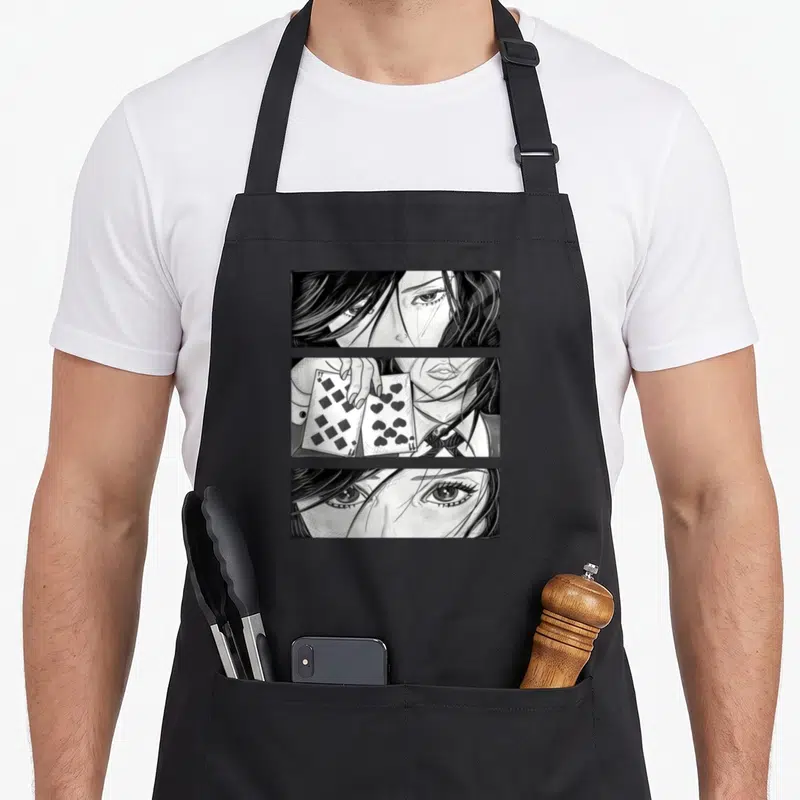 Tablier de cuisine noir avec illustration manga montrant un visage féminin et deux cartes à jouer, pique et cœur.