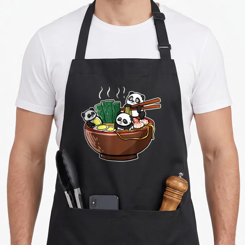 Tablier de cuisine noir avec illustration de pandas kawaii mangeant du ramen dans un bol brun.