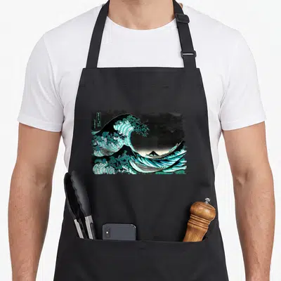 Tablier de cuisine noir avec une grande vague turquoise et le mont Fuji en arrière-plan dans un style gravure japonaise.