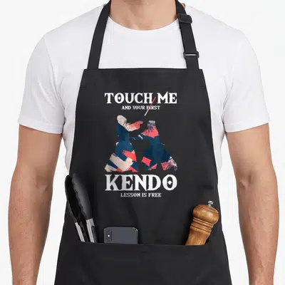 Tablier de cuisine noir avec deux silhouettes de kendo et le texte Touch Me Kendo Lesson is Free en blanc et rouge.