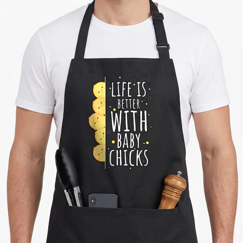 Tablier de cuisine noir avec cinq poussins jaunes kawaii et le texte Life is better with baby chicks en blanc.