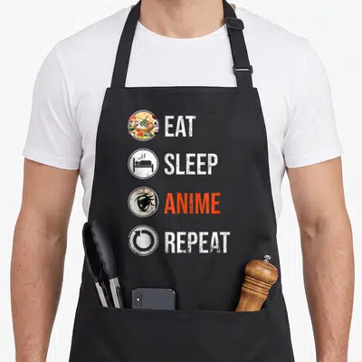 Tablier de cuisine noir avec les mots Eat Sleep Anime Repeat et des icônes circulaires colorées.