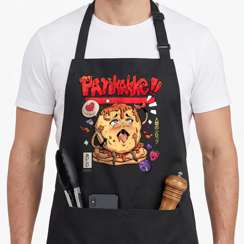 Tablier de cuisine noir avec illustration d'un pancake kawaii sous le mot Pankakke et des éléments de dessert colorés.