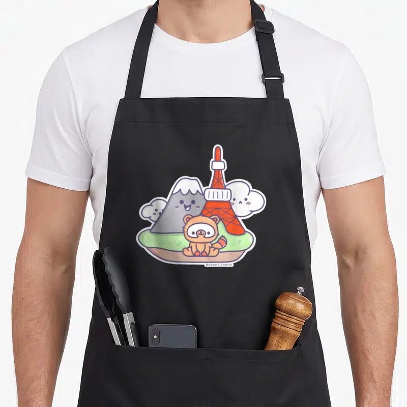 Tablier de cuisine noir avec illustration d'un Tanuki Kawaii Japan devant la Tour Eiffel et le Mont Fuji.