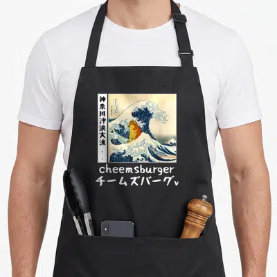 Tablier de cuisine noir avec une illustration de La Grande Vague intégrant le chien Cheems et le texte cheemsburger.