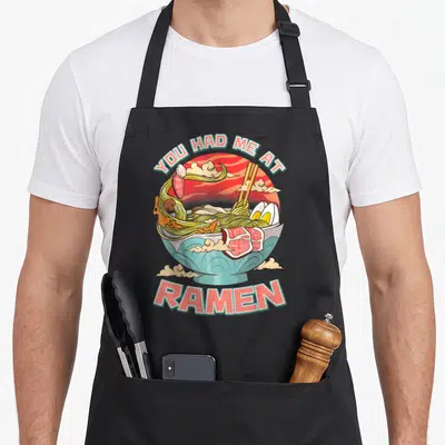 Tablier de cuisine noir avec illustration colorée d'un bol de ramen et le texte You Had Me At Ramen en lettres roses.