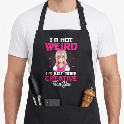 Tablier de cuisine noir avec une illustration anime rose et le texte I'm Not Weird I'm Just More Creative Than You.