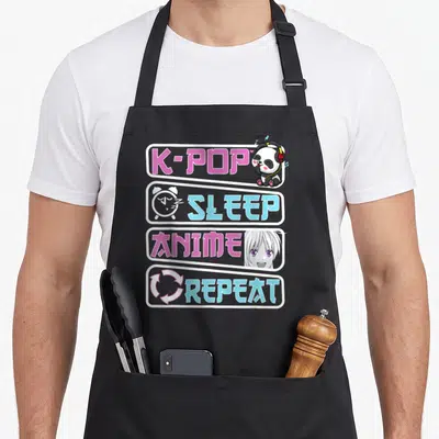 Tablier de cuisine noir avec inscriptions K-Pop Sleep Anime Repeat et illustrations panda et personnage manga.
