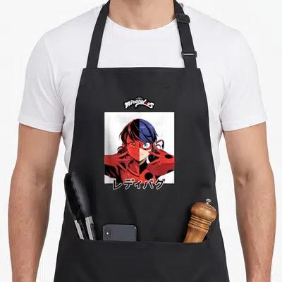 Tablier de cuisine noir avec un portrait manga divisé de Ladybug et Marinette sur fond blanc.