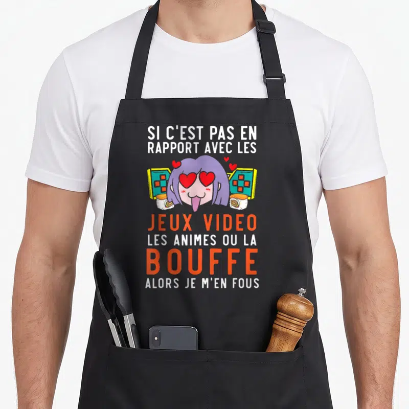 Tablier de cuisine noir avec une illustration manga de fille aux yeux de cœur, sushi et console de jeu vidéo.