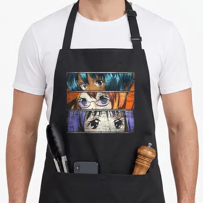 Tablier de cuisine noir avec trois segments d'illustrations manga aux cheveux colorés et grands yeux expressifs.