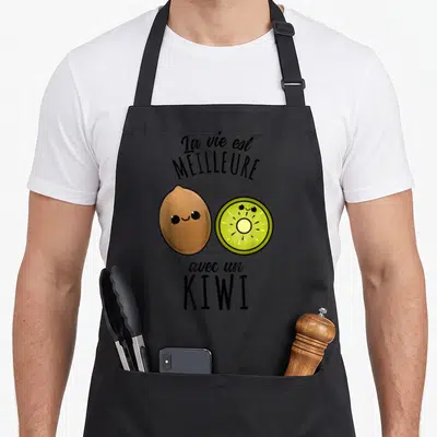 Tablier de cuisine noir avec un kiwi entier et une tranche kawaii souriants sous le texte La vie est meilleure avec un kiwi.