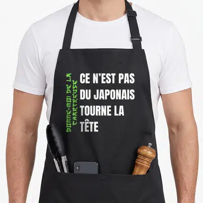 Tablier de cuisine noir avec le texte blanc Ce n'est pas du japonais tourne la tête et une ligne verte verticale.