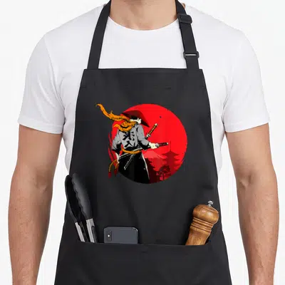 Tablier de cuisine noir avec illustration d'un samouraï au chapeau conique devant un disque rouge vif.