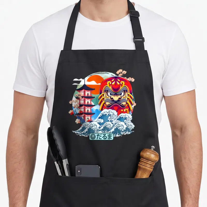Tablier de cuisine noir avec illustration d'un Daruma rouge, d'une vague bleue et d'une pagode japonaise.