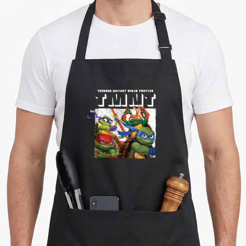 Tablier de cuisine noir avec illustration des quatre tortues ninja et le logo TMNT en blanc.
