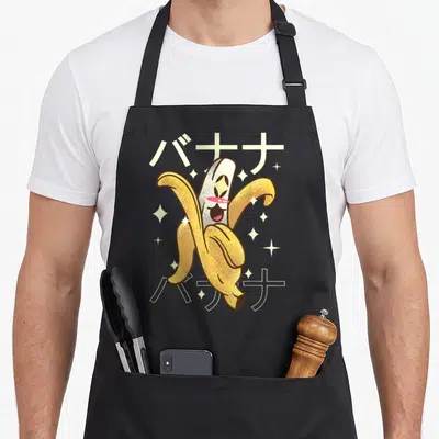 Tablier de cuisine noir avec une banane anthropomorphée jaune aux yeux ronds et des caractères japonais en arrière-plan.