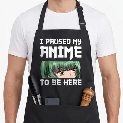 Tablier de cuisine noir avec une illustration de visage aux cheveux verts et texte blanc stylisé.