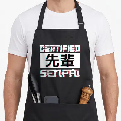 Tablier de cuisine noir avec inscription Certified Senpai en typographie glitch blanche et noire aux contours cyan et rouge.