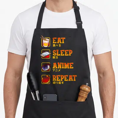 Tablier de cuisine noir avec les mots EAT SLEEP ANIME REPEAT et icônes manga japonaises en orange et jaune.