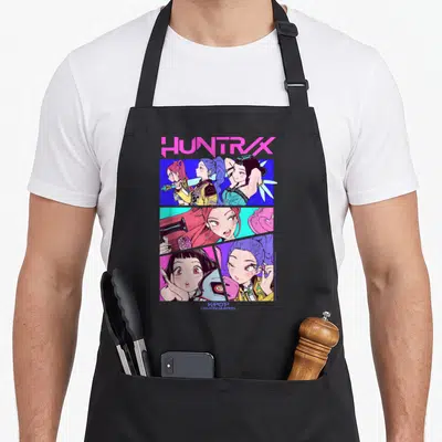 Tablier de cuisine noir avec une illustration colorée du groupe Huntrix en style comic book néon.
