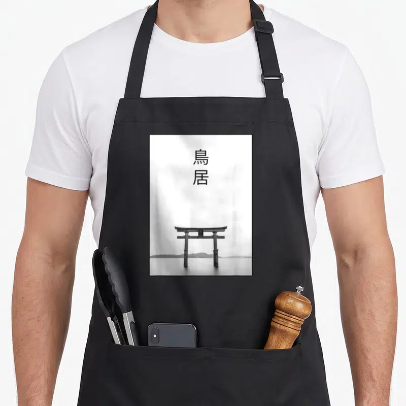 Tablier de cuisine noir avec illustration d'un Torii Gate et deux caractères japonais au centre.