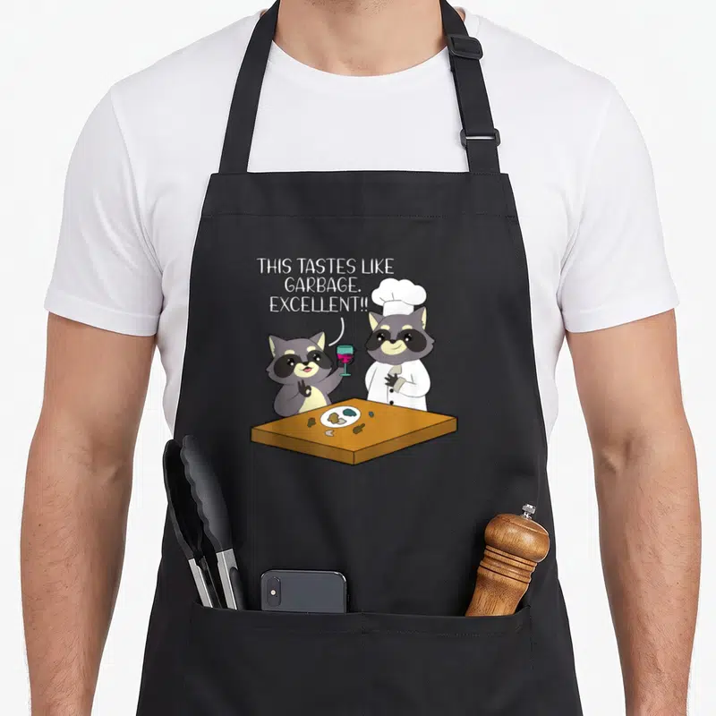 Tablier de cuisine noir avec un raton laveur chef et un ami tenant un verre de vin rouge devant une table.
