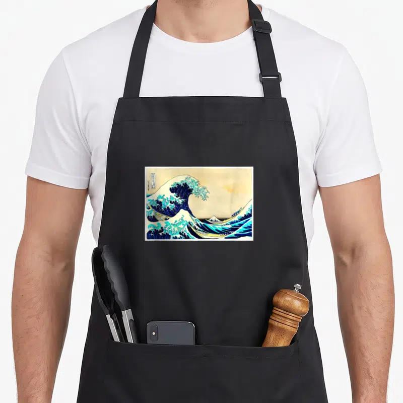 Tablier de cuisine noir avec reproduction de La Grande Vague de Hokusai en estampe ukiyo-e vintage.