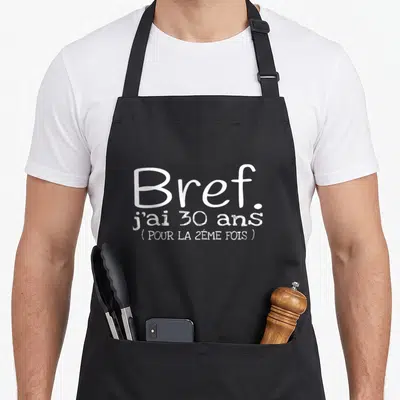 Tablier de cuisine noir avec l'inscription blanche Bref j'ai 30 ans pour la 2ème fois imprimée au centre.