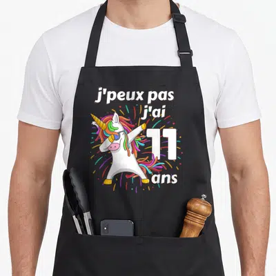 Tablier de cuisine noir avec licorne colorée effectuant un mouvement de danse et le chiffre 11 en blanc.