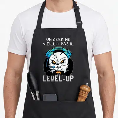 Tablier de cuisine noir avec un panda gamer aux yeux orange portant des écouteurs et tenant une manette de jeu vidéo.