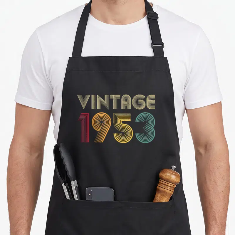Tablier de cuisine noir avec l'inscription Vintage 1953 en lettres colorées au design rétro des années cinquante.