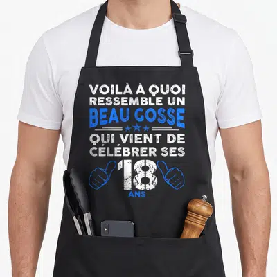 Tablier de cuisine noir avec inscription blanche et bleue célébrant les 18 ans d'un jeune homme.