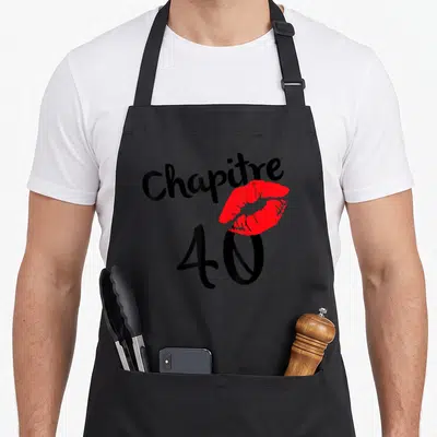 Tablier de cuisine noir avec l'inscription Chapitre 40 et une empreinte de lèvres rouges stylisées au centre du design.