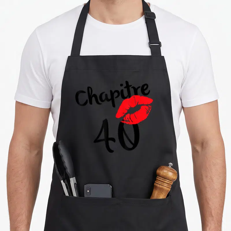 Tablier de cuisine noir avec linscription Chapitre 40 et une empreinte de lèvres rouges stylisées au centre du design.