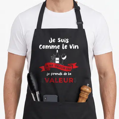 Tablier de cuisine noir avec texte blanc et rouge Je suis comme le vin et une illustration de bouteille et verre.