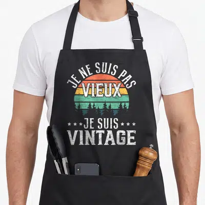 Tablier de cuisine noir avec inscription Je ne suis pas vieux je suis vintage sur fond de soleil rétro et arbres.
