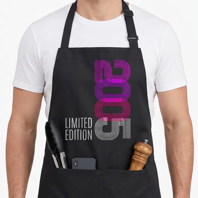 Tablier de cuisine noir avec l'année 2005 stylisée en lignes roses et blanches et le texte Limited Edition en blanc.