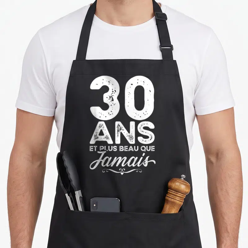 Tablier de cuisine noir avec l'inscription 30 ans et plus beau que jamais en typographie blanche vintage.