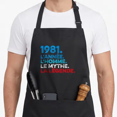 Tablier de cuisine noir avec inscription 1981 l'année l'homme le mythe la légende en bleu et rouge.