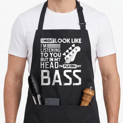 Tablier de cuisine noir avec inscription blanche sur la musique et illustration d'une tête de guitare basse.